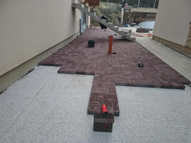 Vörös téglakő parketta-kötésben ház mellett, zúzottkő ágyazaton, lerakás közben